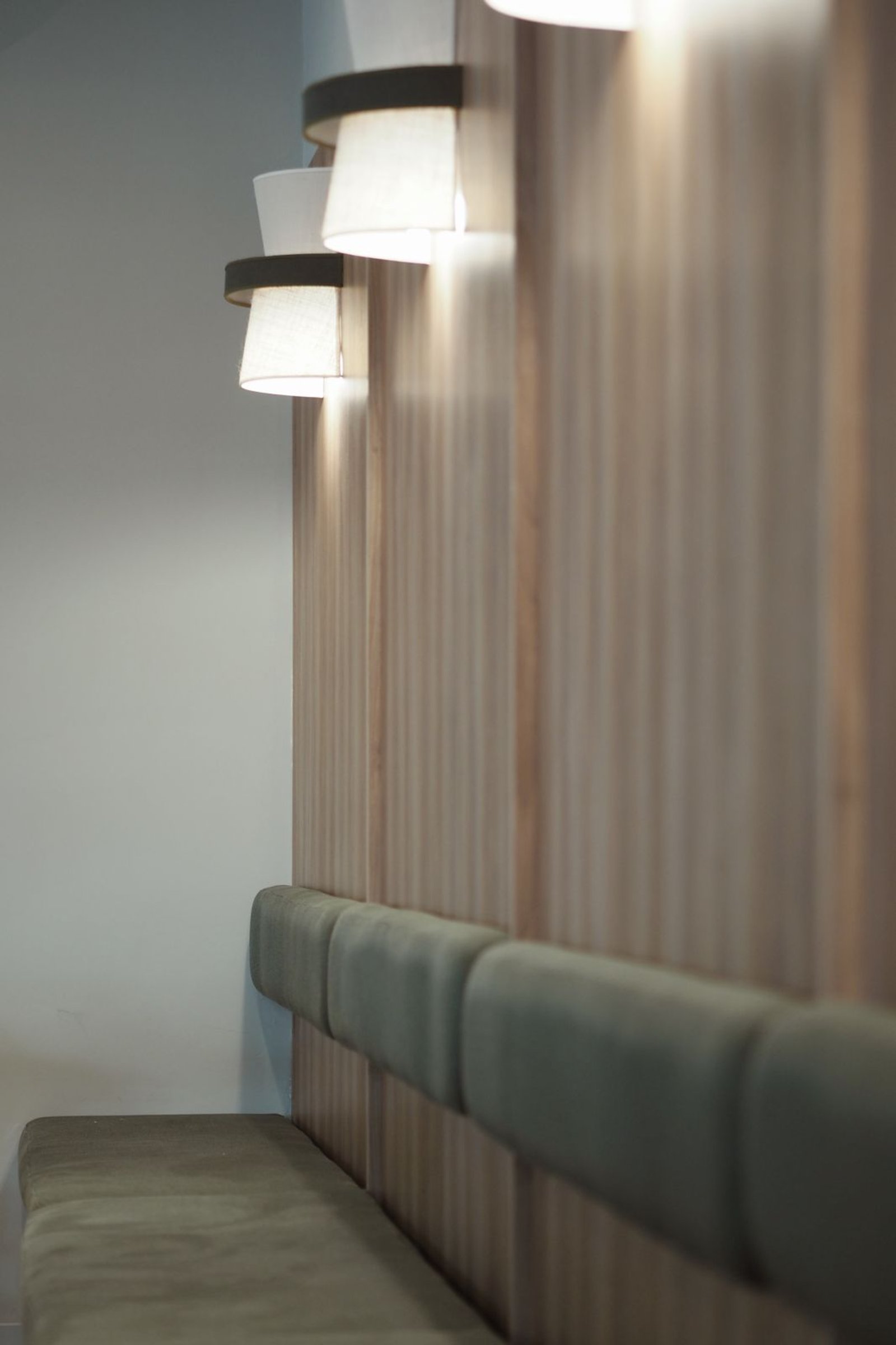 Banqueta verde junto a pared de madera con luces — proyecto FOMO CAFÉ, por APATHEIA, en Vicente López